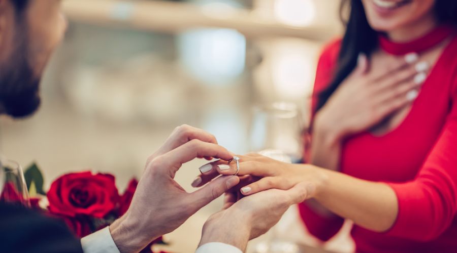 man putting ring on woman's finger