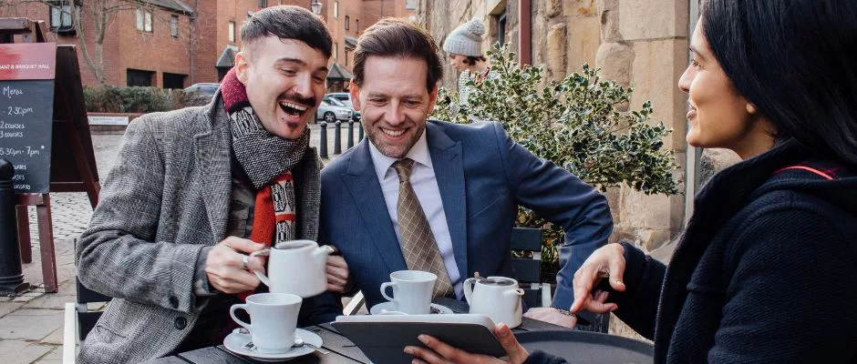 Same-sex couple at a coffee shop looking at a tablet in person's hand