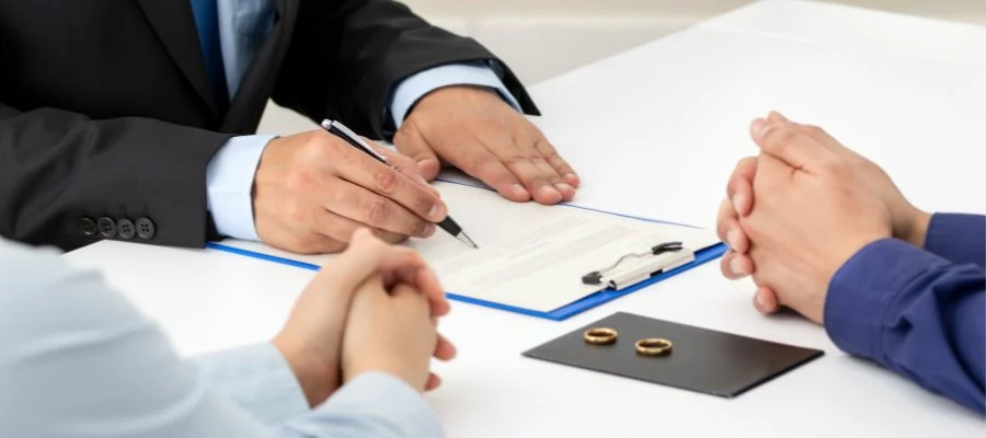couple sitting at a table with rings on top next to paperwork
