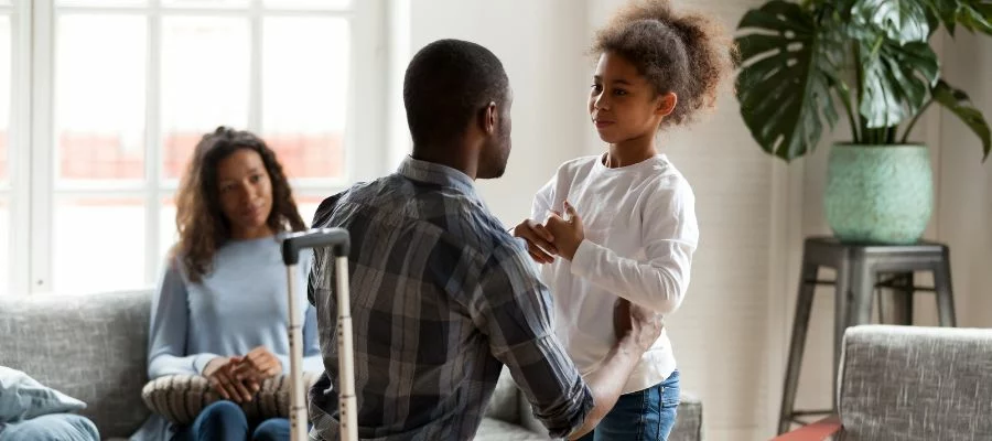 father holding daughter in front of mom sitting on a couch